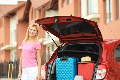 Photo of Happy woman near car trunk with suitcases outdoors