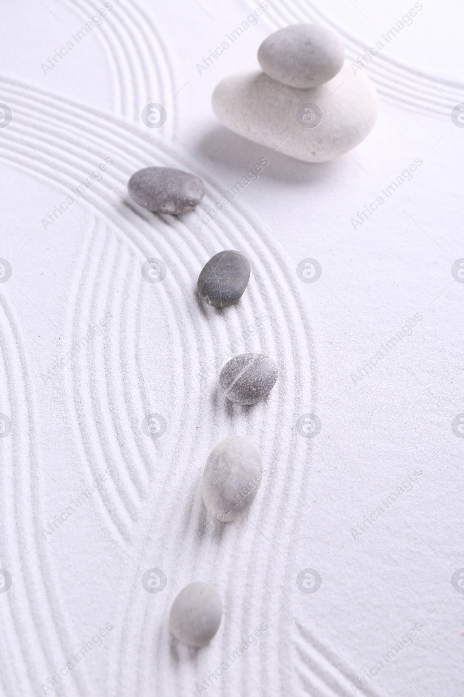 Photo of Zen garden stones on white sand with pattern, flat lay