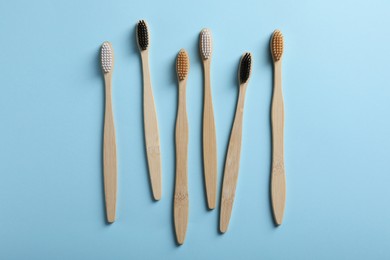 Bamboo toothbrushes on light blue background, flat lay