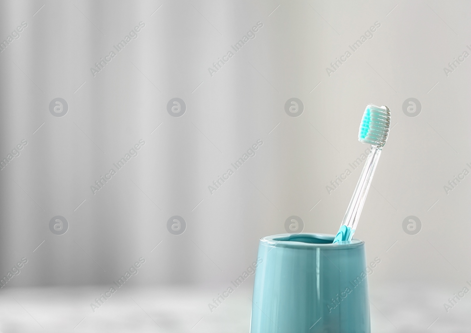 Photo of Cup with toothbrush against blurred background. Dental care