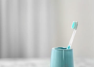 Photo of Cup with toothbrush against blurred background. Dental care