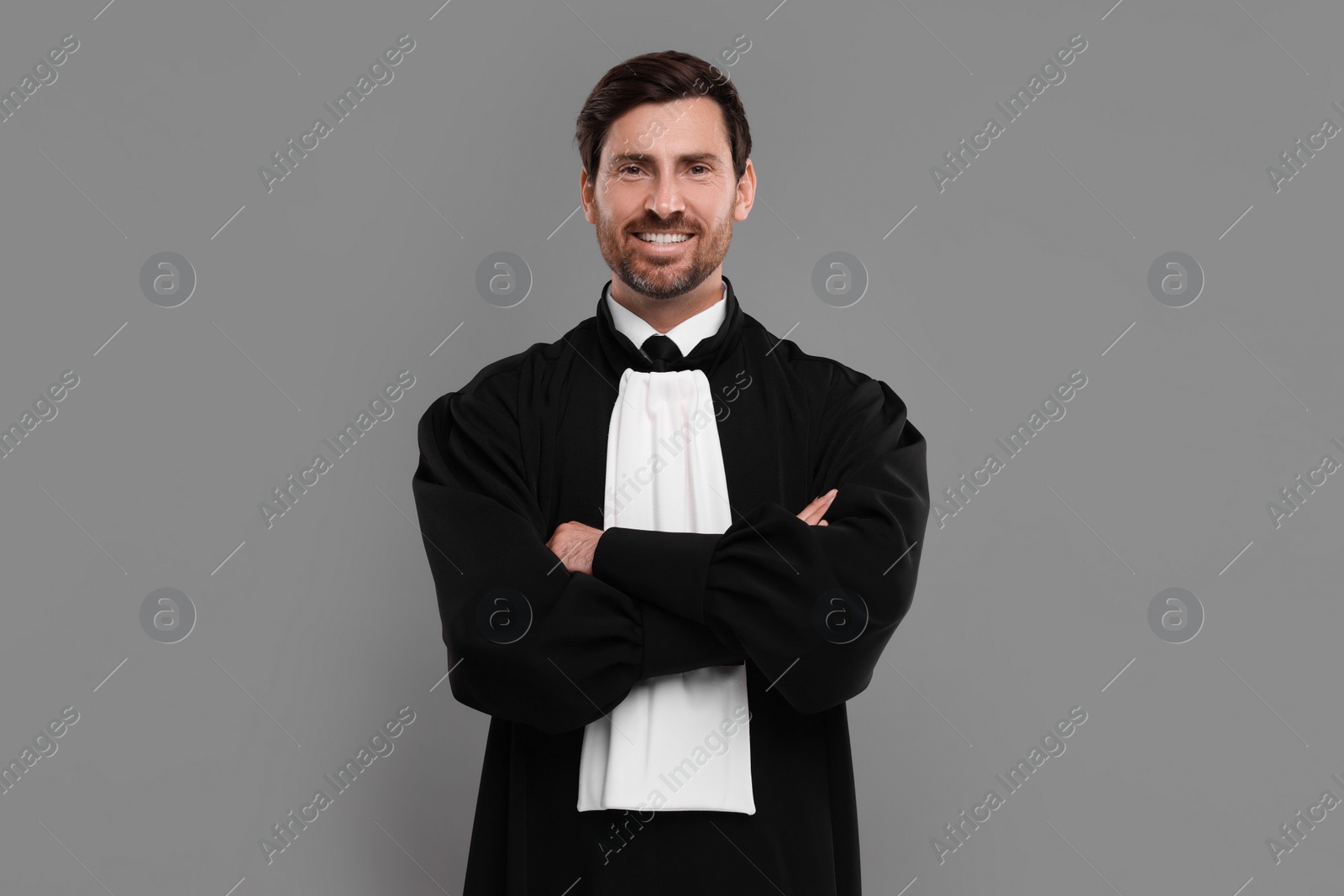 Photo of Smiling judge with crossed arms on grey background