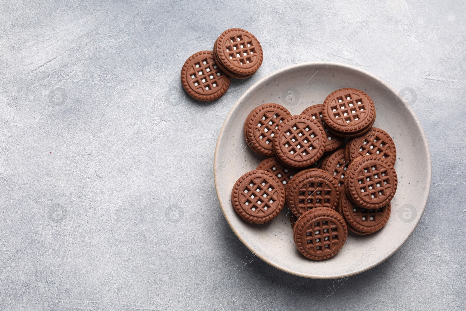 Photo of Tasty chocolate sandwich cookies with cream on light grey table, flat lay. Space for text