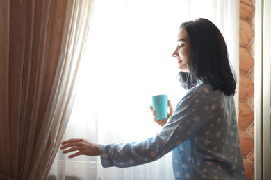 Young woman with drink near window at home. Lazy morning