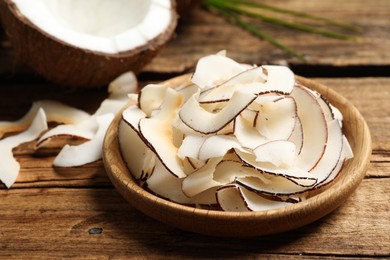 Delicious coconut chips in plate on wooden table