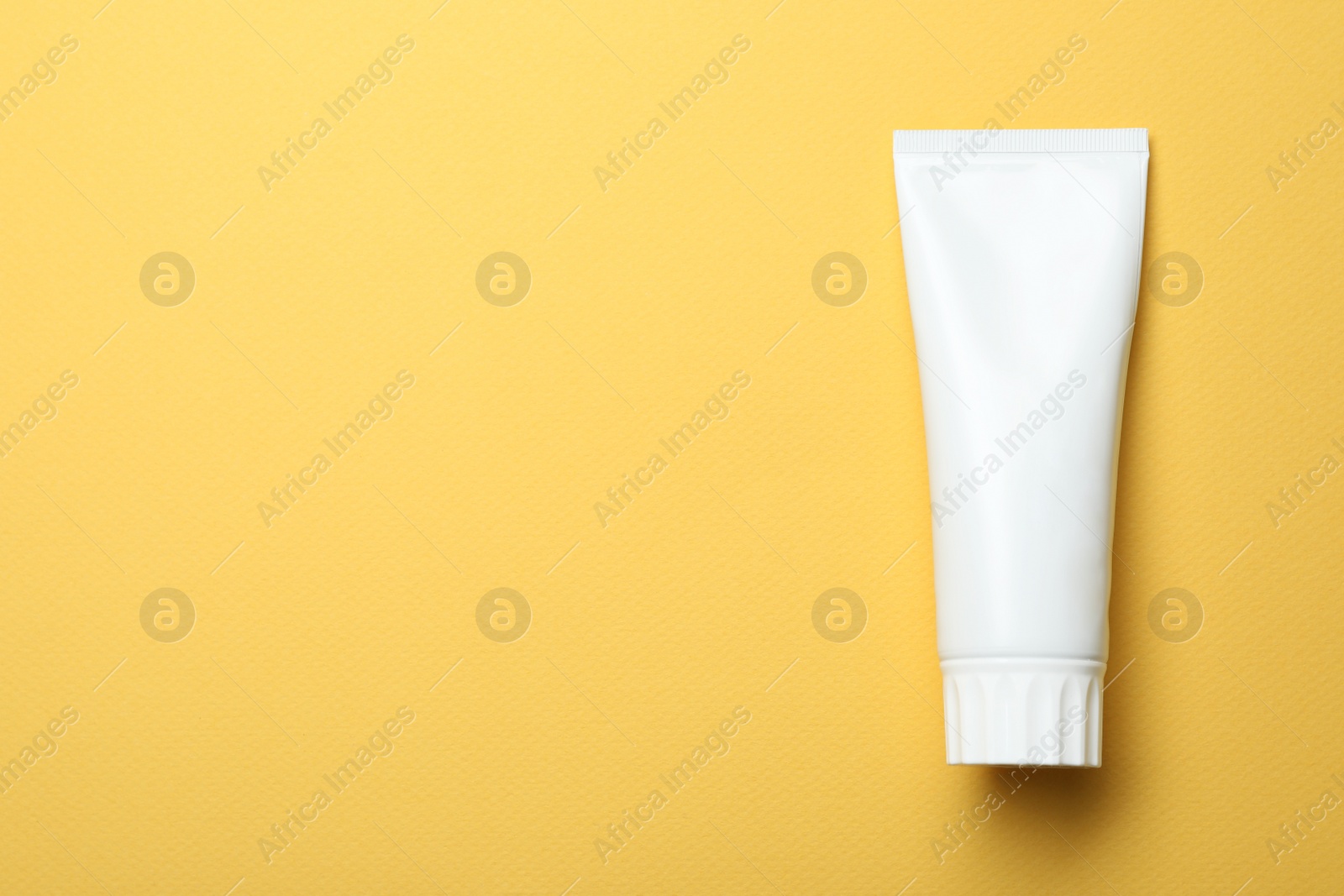 Photo of Blank tube of toothpaste on color background, top view with space for text