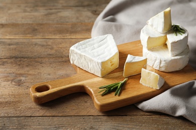 Photo of Wooden board with delicious cheeses on table