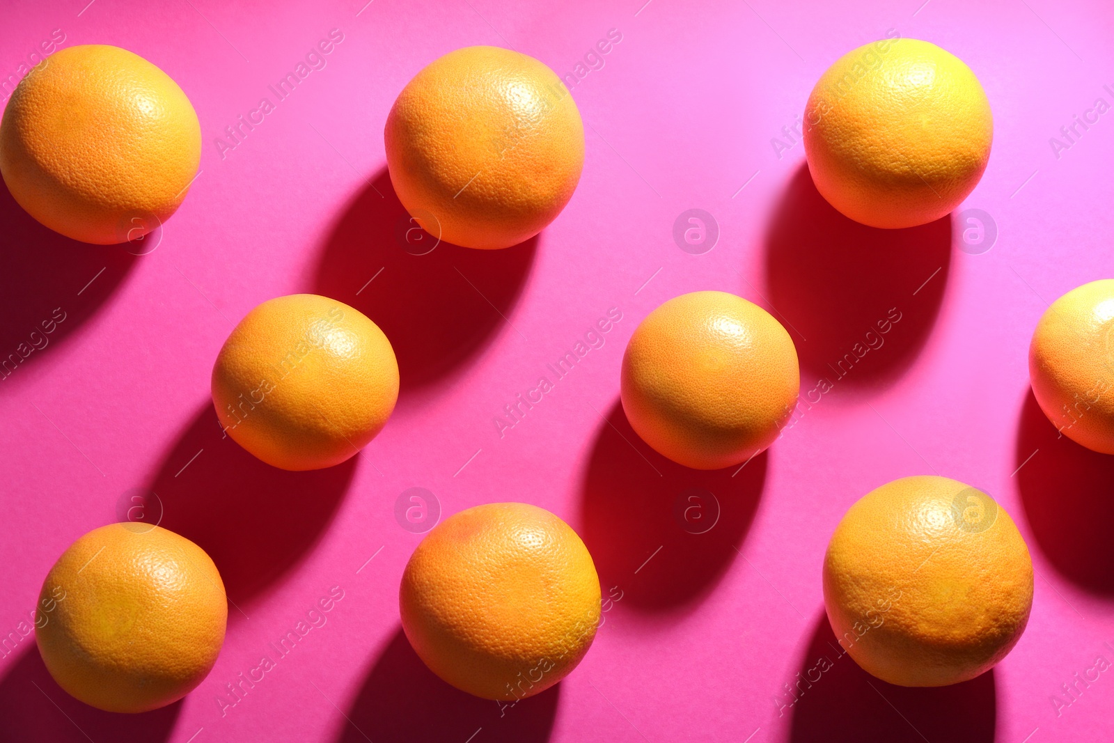 Photo of Tasty ripe grapefruits on magenta background, flat lay