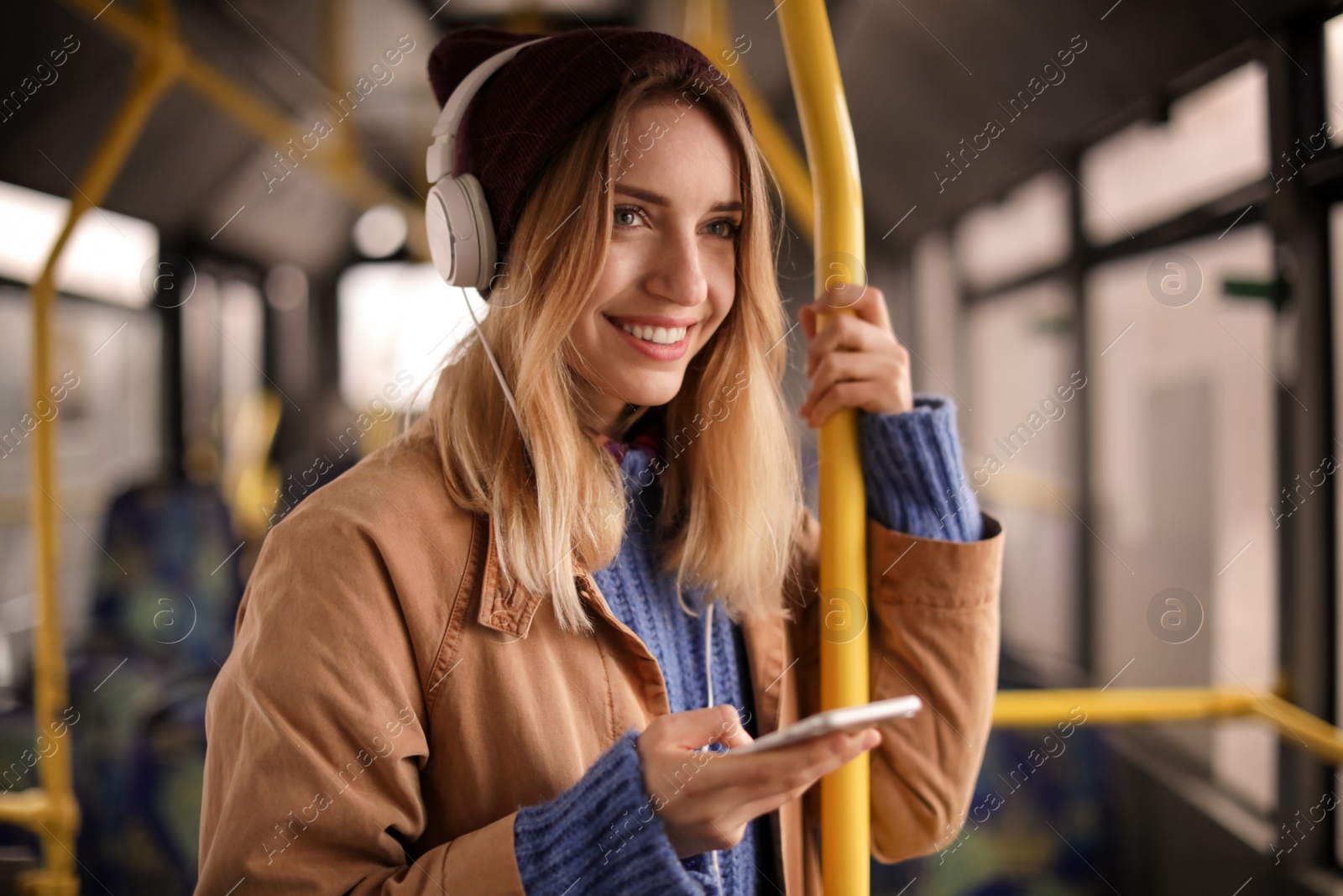 Photo of Young woman with headphones listening to music in public transport