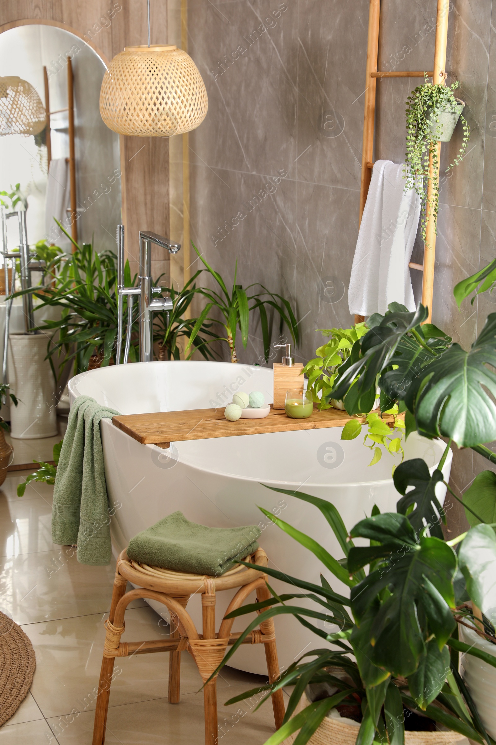 Photo of Modern white tub and beautiful green houseplants in bathroom. Interior design