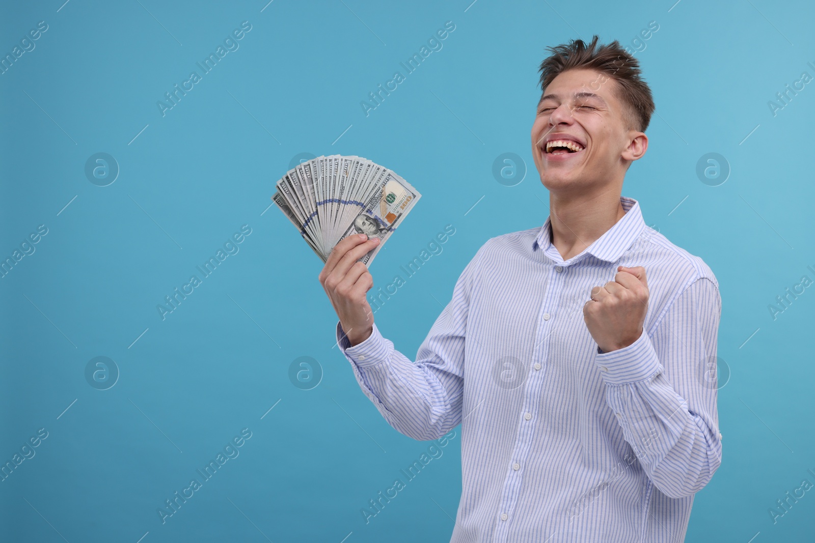 Photo of Happy man with dollar banknotes on light blue background. Space for text