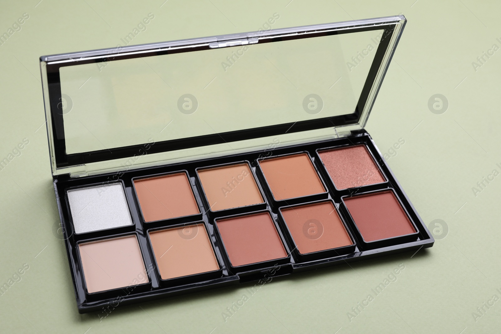 Photo of Colorful contouring palette on pale green background, closeup. Professional cosmetic product
