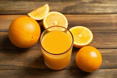 Photo of Glass of orange juice and fresh fruits on wooden background