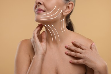 Woman with perfect skin after cosmetic treatment on beige background, closeup. Lifting arrows on her neck and face