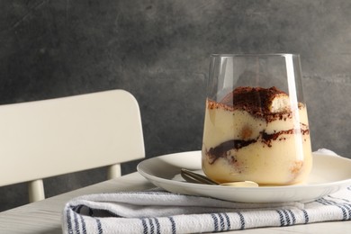 Photo of Delicious tiramisu in glass on white wooden table, closeup. Space for text