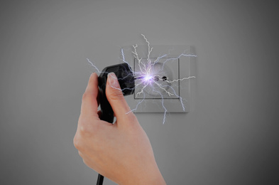 Image of Woman receiving electric shock while unplugging, closeup