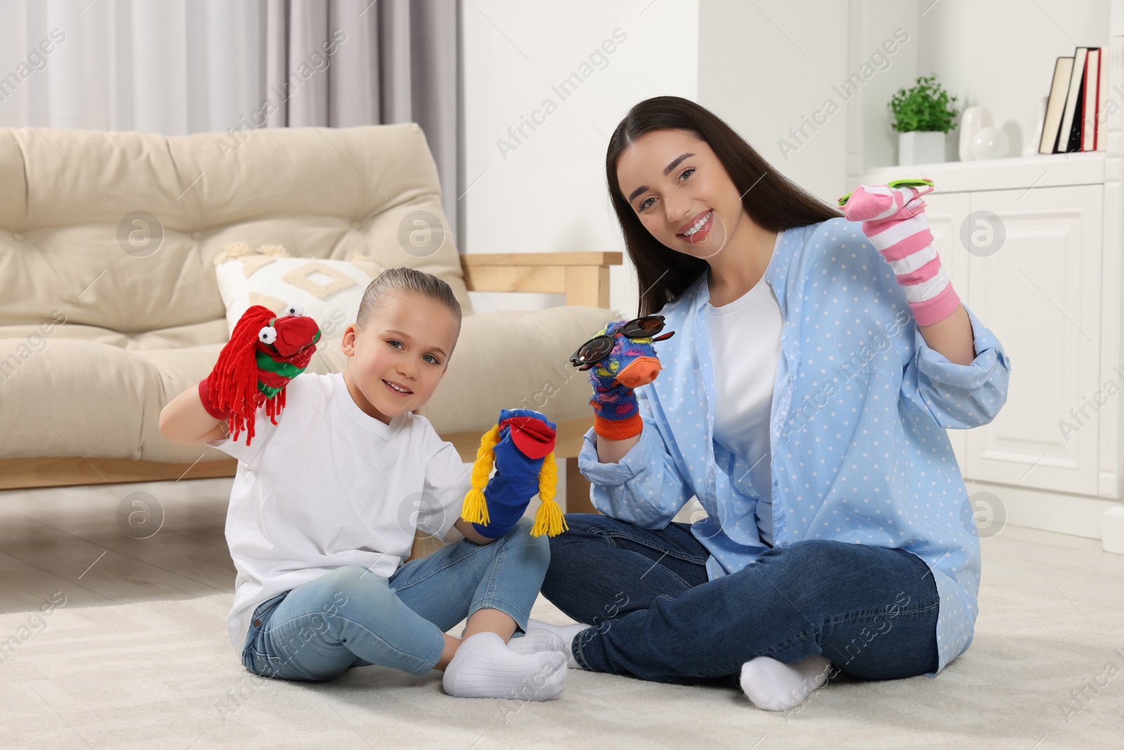 Photo of Happy mother and daughter playing with funny sock puppets together at home