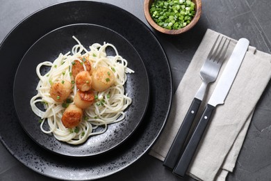 Delicious scallop pasta with green onion served on grey table, flat lay