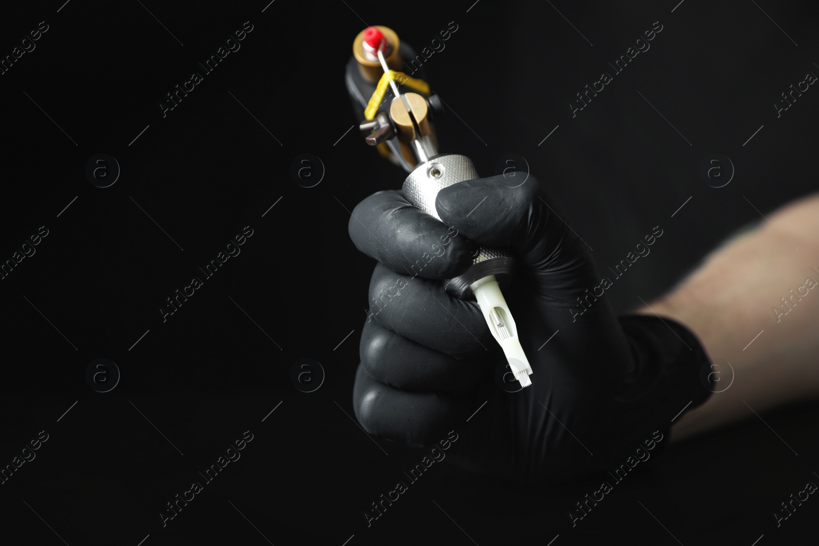 Photo of Tattoo artist with professional machine on black background, closeup