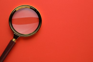 Photo of Magnifying glass on red background, top view. Space for text
