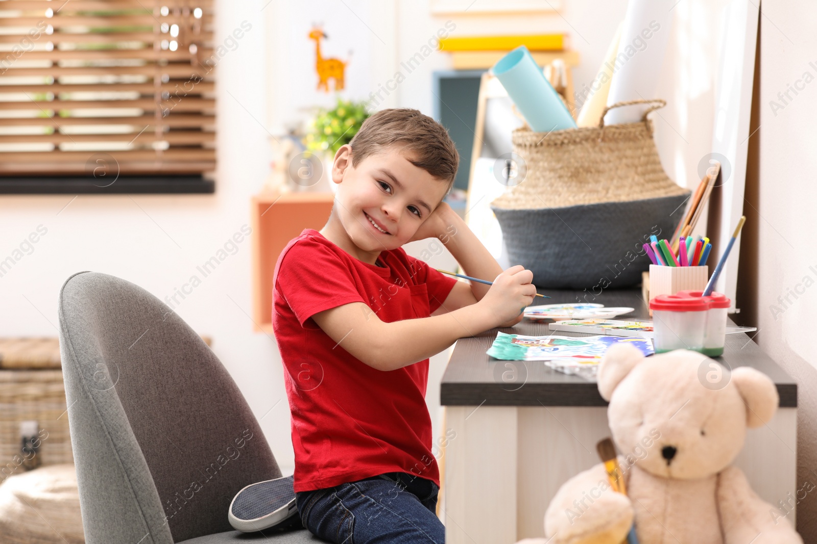 Photo of Little child painting at table in room