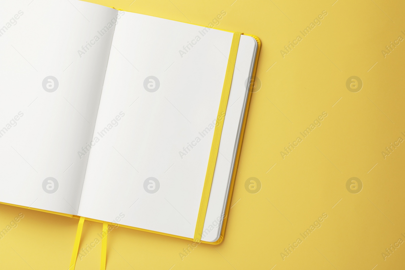 Photo of Blank notebook on pale yellow background, top view. Space for text