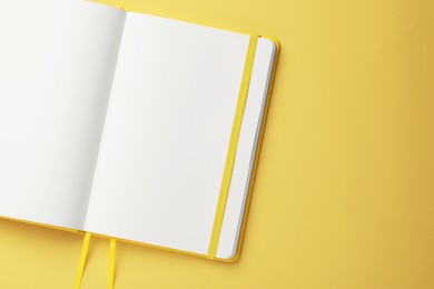 Photo of Blank notebook on pale yellow background, top view. Space for text