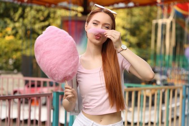 Photo of Beautiful woman having fun with cotton candy at funfair