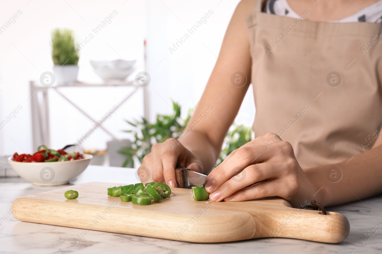 Photo of Woman cutting chili peppers at table, closeup