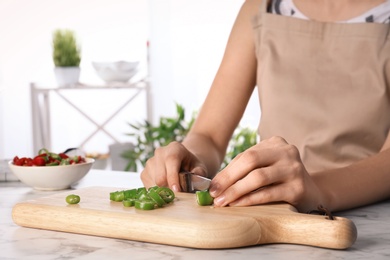 Woman cutting chili peppers at table, closeup