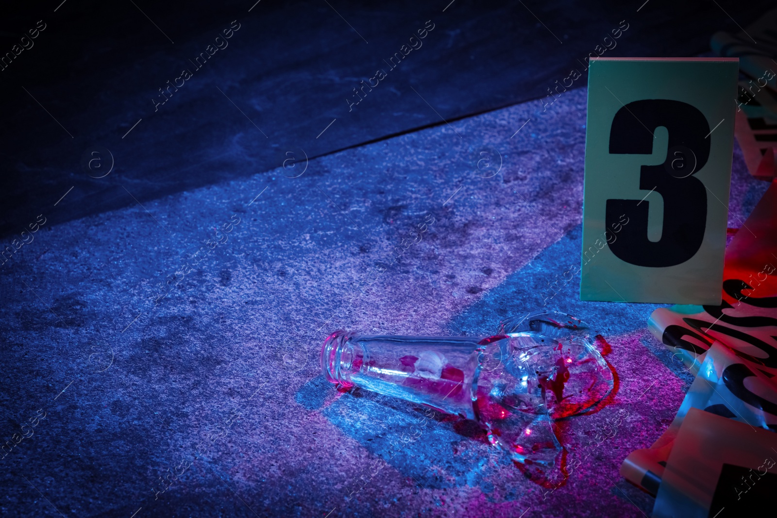 Photo of Broken bottle and crime scene marker on stone background, toned in blue and red