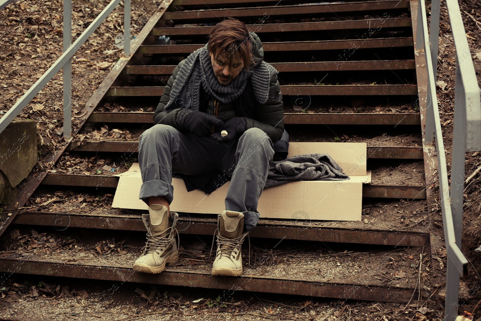 Photo of Poor young man sitting on stairs outdoors
