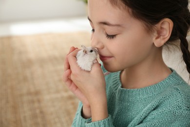 Photo of Little girl with cute hamster at home. Space for text