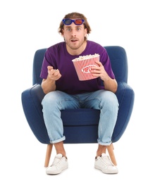 Emotional man with 3D glasses and popcorn sitting in armchair during cinema show on white background