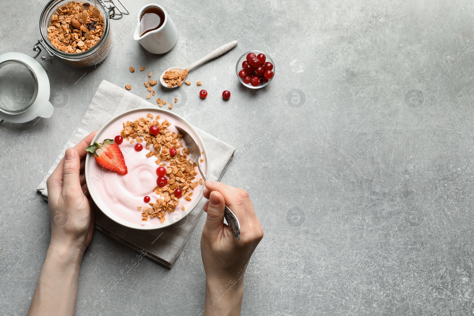 Photo of Woman eating tasty yogurt with berries and granola at table, top view