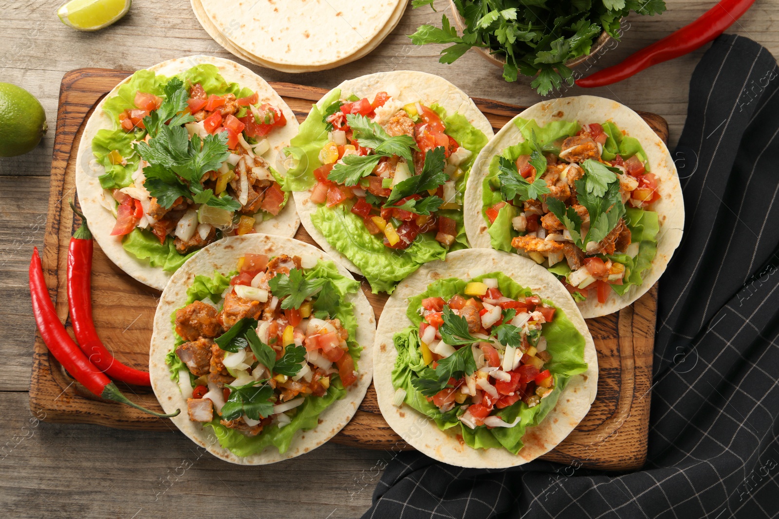 Photo of Delicious tacos with vegetables and meat on wooden table, flat lay