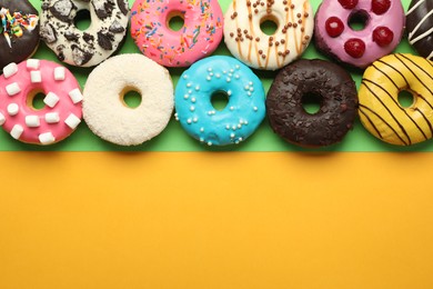 Sweet tasty glazed donuts on color background, flat lay. Space for text