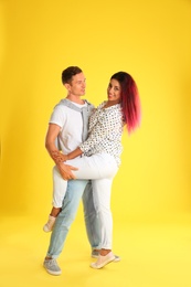 Beautiful lovely couple dancing on yellow background