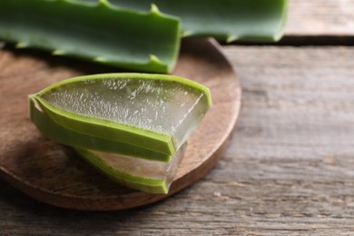 Photo of Slices of fresh aloe vera leaves with gel on wooden table, closeup. Space for text