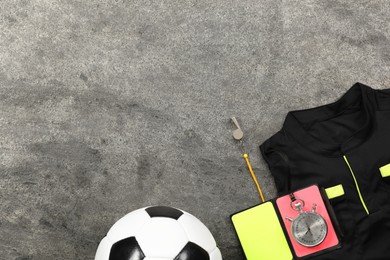Photo of Referee jersey, soccer ball and other equipment on grey table, top view. Space for text