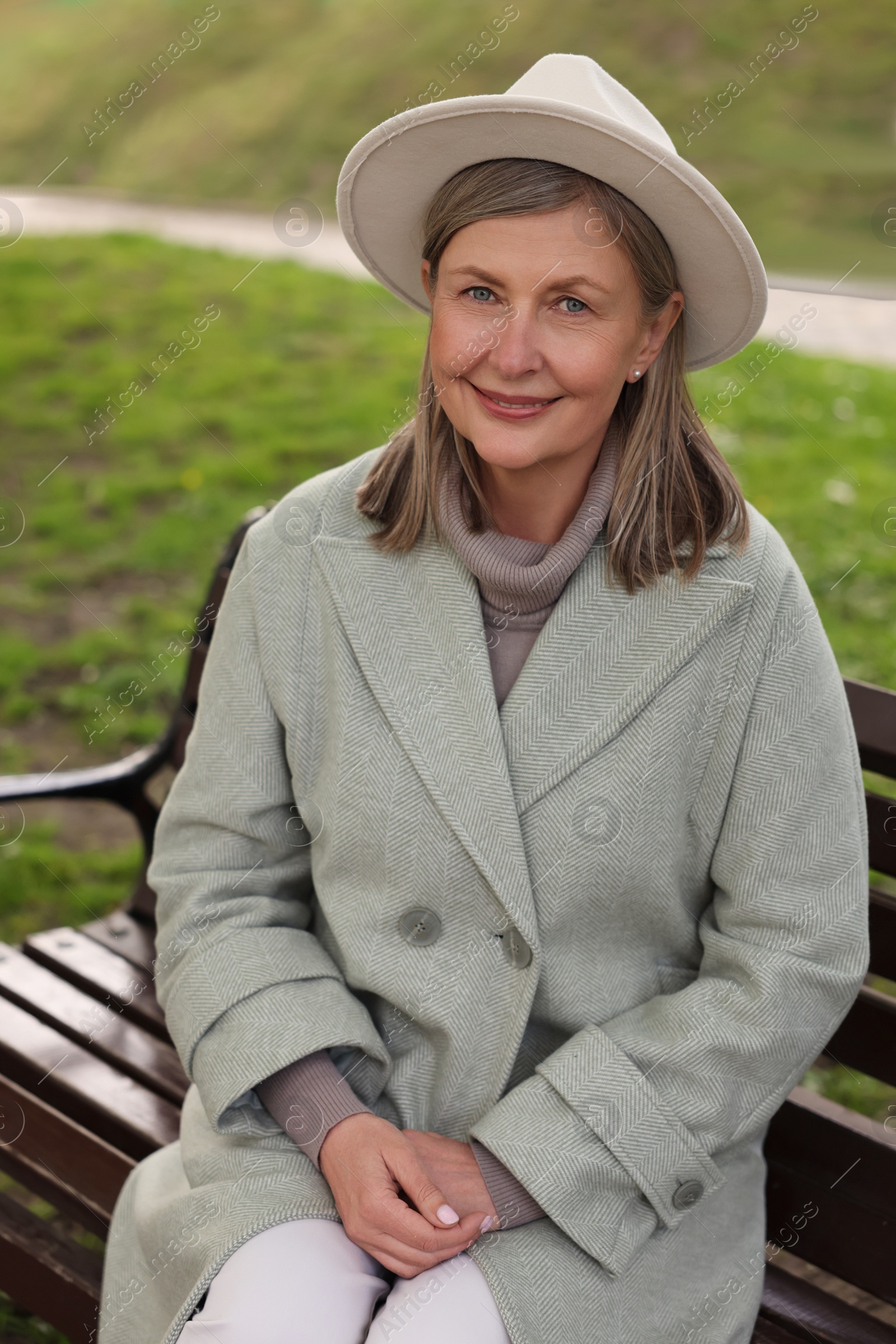 Photo of Beautiful senior woman sitting on bench outdoors