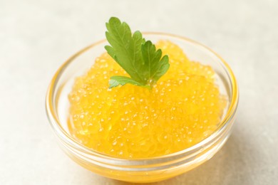 Fresh pike caviar in bowl and parsley on light grey table, closeup