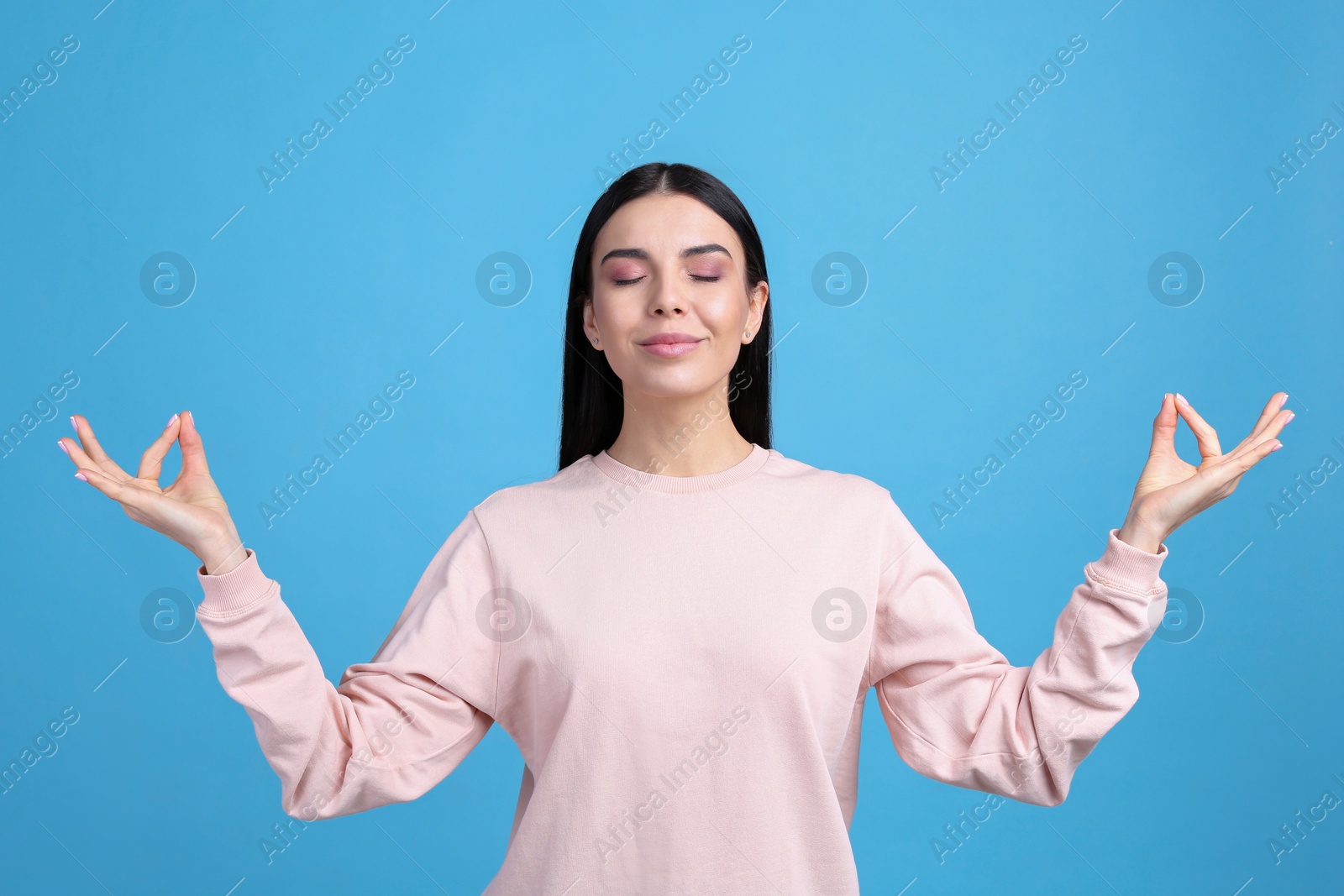 Photo of Young woman meditating on light blue background. Stress relief exercise