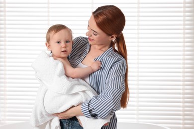 Photo of Mother holding cute little baby wrapped with towel indoors after bath