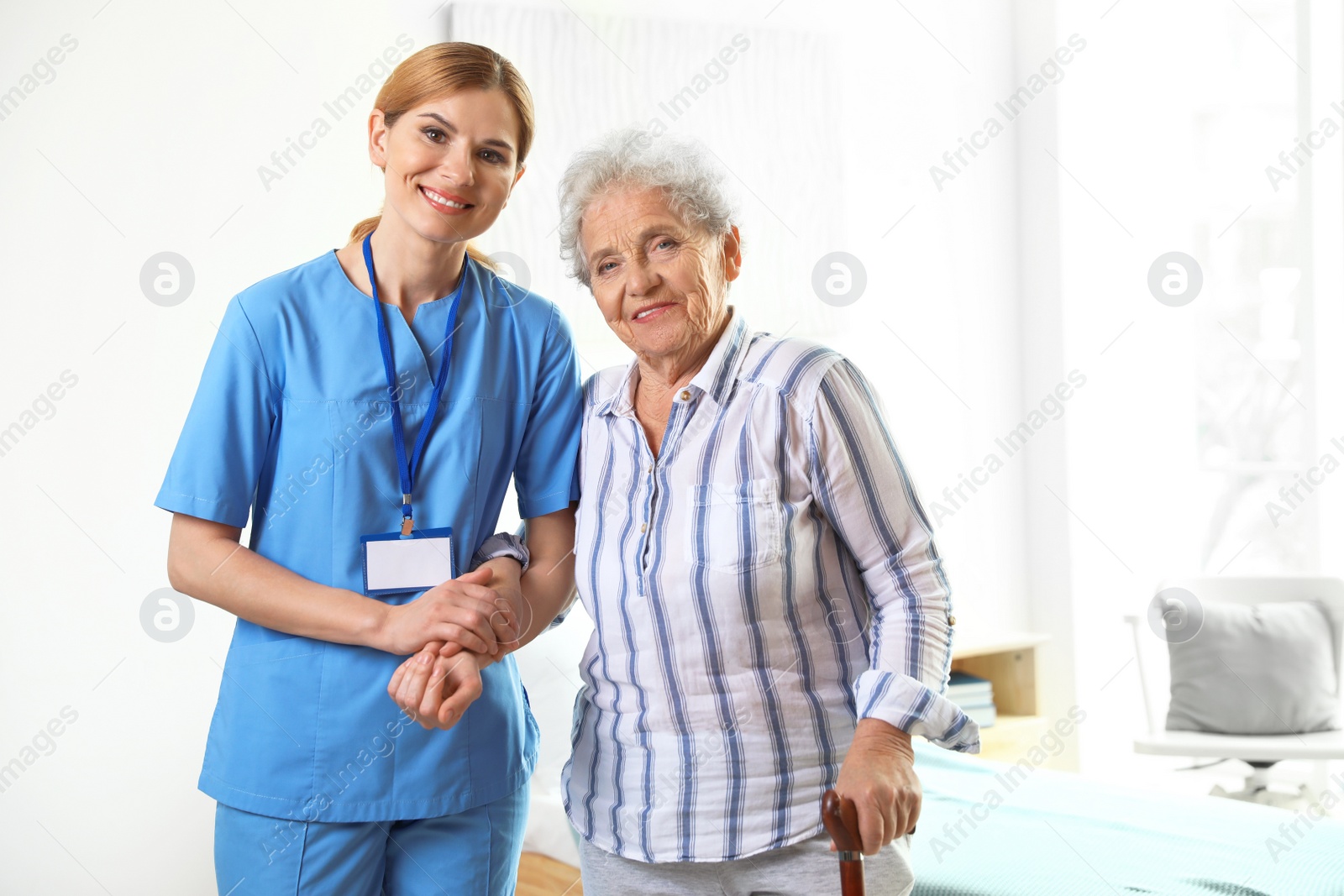 Photo of Nurse in uniform assisting elderly woman indoors