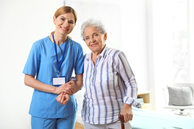 Nurse in uniform assisting elderly woman indoors