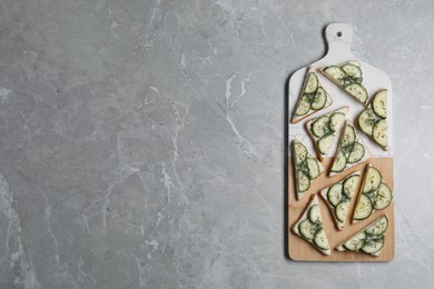 Photo of Tasty sandwiches with cream cheese, cucumber and dill on grey marble table, flat lay. Space for text