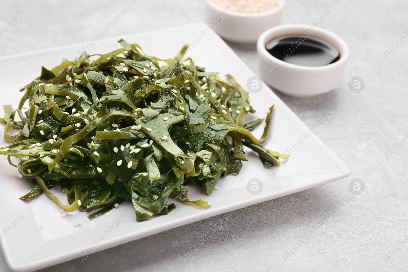 Photo of Fresh laminaria (kelp) seaweed served on light gray table, closeup