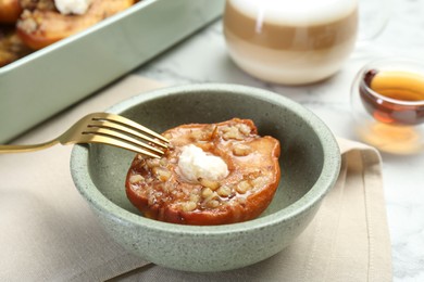 Tasty baked quince with nuts and cream cheese in bowl on table, closeup