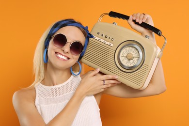 Photo of Happy hippie woman with retro radio receiver on orange background